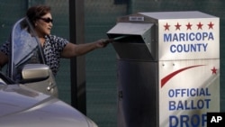 Una votante emite su voto en un buzón seguro en el Centro Electoral y de Tabulación del Condado de Maricopa en Phoenix, Arizona, el martes 1 de noviembre de 2022. (Foto AP/Matt York)