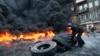 A protester prepares to throw a tire onto a fire during clashes with police in central Kiev, Ukraine, Jan. 25, 2014.