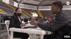 Migrante venezolano le entrega información a una funcionario de Migración Colombia, minutos antes de recibir el Permiso de Protección Temporal (PPT), el 21 de noviembre de 2022. [Foto: Camilo Álvarez, VOA]