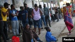 Migrantes de Haití hacen fila para regularizar su situación migratoria fuera de la Comisión Mexicana de Ayuda a Refugiados (COMAR), en Tijuana, México, el 29 de septiembre de 2021.
