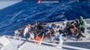 In this image taken from a video released by the Italian Coast Guard, April 11, 2024, a boat with migrants is approached by a rescue operation off the island of Lampedusa in the Mediterranean Sea.