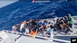 In this image taken from a video released by the Italian Coast Guard, April 11, 2024, a boat with migrants is approached by a rescue operation off the island of Lampedusa in the Mediterranean Sea.