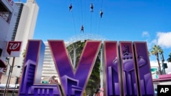 People ride a zip line above a sign for the Super Bowl ahead of the Super Bowl 58 NFL football game, Feb. 2, 2024, in Las Vegas.