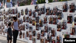Una mujer y un niño caminan junto fotografías dedicadas a los rehenes que están retenidos en Gaza después de que fueron secuestrados en Israel por hombres armados de Hamás el 7 de octubre. En Tel Aviv, Israel, el 3 de noviembre de 2023.