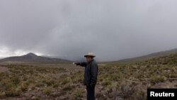 Un hombre señala una nube de ceniza del volcán Ubinas, en Santiago de Machaca, Bolivia, a lo largo de la frontera con Perú, el 20 de julio de 2019.