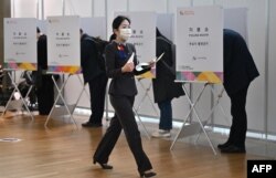 Seorang pegawai maskapai penerbangan memberikan suaranya saat pemungutan suara awal di tempat pemungutan suara di aula keberangkatan Bandara Internasional Incheon, 5 April 2024, menjelang pemilihan parlemen minggu depan. (Jung Yeon-je / AFP)