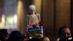ARCHIVO: Una mujer sostiene un esqueleto con un cartel que dice en español "Cuidado, el machismo mata" durante una marcha convocada por asociaciones feministas de Ecuador contra la violencia de género en Quito, Ecuador, el sábado 26 de noviembre de 2016.