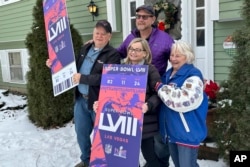 Don Crisman, far left, poses with his wife, Beverley, far right, his daughter Sue Metevier, and her partner Charles Hugo, with posters of Super Bowl 58 tickets, in Kennebunk, Maine, Jan. 18, 2024.
