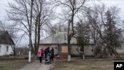 Una familia sale después de visitar a un voluntario médico de FRIDA Ucrania en la aldea de Khrestysche, región de Donetsk, Ucrania, el domingo 19 de marzo de 2023.