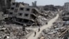 FILE - Palestinians ride bicycles past the ruins of houses and buildings destroyed during Israel’s military offensive in the northern Gaza Strip, March 31, 2024. 