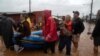 Residents and a dog are evacuated from a flooded area of Sao Sebastiao do Cai, Rio Grande do Sul State, Brazil, on May 2, 2024. 