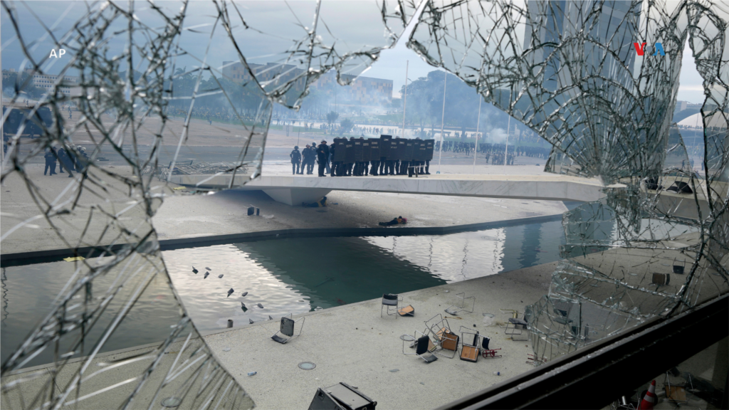  Policía en posición de guardia al otro lado de una ventana quebrada por simpatizantes del presidente saliente Jair Bolsonaro, que irrumpieron el palacio presidencial de Planalto en un presunto intento de forzar su regreso al poder, en Brasilia, Brasil, el 8 de enero de 2023. &nbsp; &nbsp; 