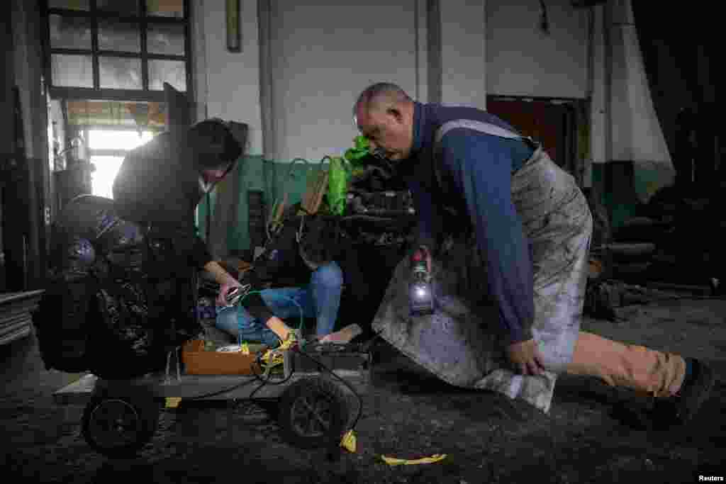 Dmytro Mamonov, su esposa Oksana y su hijo Yelisei, miran un vehículo de prueba en su taller, el 31 de mayo.de 2024. REUTERS/Thomas Peter
