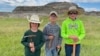 In this image provided by Giant Screen Films, Liam Fisher, Kaiden Madsen and Jessin Fisher pose for a celebratory photo on the day their fossil find was determined to be a juvenile T. rex, in North Dakota. 