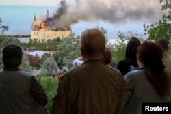 Orang-orang melihat gedung lembaga pendidikan yang terbakar pasca serangan rudal Rusia, di tengah serangan Rusia ke Ukraina, di Odesa, Ukraina, 29 April 2024. (Foto: REUTERS/Sergey Smolentsev)