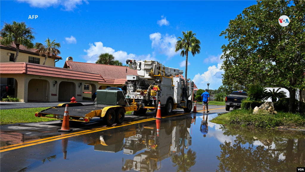 La imagen muestra a un hombre que pasa junto a un camión de limpieza en una calle inundada en Crystal River, Florida, el 31 de agosto de 2023.