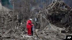 Un trabajador médico consuela a una mujer en el lugar de un ataque aéreo ruso, en Zaporizhzhia, Ucrania, el 22 de marzo de 2024.