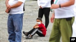 Un niño se sienta en medio de excombatientes de las FARC para una ceremonia en la que exrebeldes se disculparon con los lugareños por los secuestros llevados a cabo por las FARC durante décadas en la zona rural de Pipiral cerca de Villavicencio, Colombia, 29 de octubre de 2020.