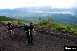 Pendaki berjalan di Jalur Fuji Yoshida Guchi pada hari pertama musim pendakian di lereng Gunung Fuji, di Fujiyoshida, Prefektur Yamanashi, Jepang, 1 Juli 2024. (Foto: Reuters)