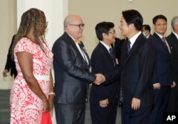 El vicepresidente de Taiwán, William Lai, a la derecha, le da la mano al encargado de negocios Carlos Pintos de Paraguay antes de partir hacia Paraguay en el Aeropuerto Internacional de Taoyuan en Taoyuan, Taiwán, el sábado 12 de agosto de 2023. (Foto AP/Chiang Ying-ying )