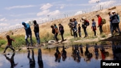 Migrantes que buscan asilo cruzan el Río Bravo para regresar a México desde Estados Unidos, luego de que miembros de la Guardia Nacional de Texas extendieran alambre de púas para impedir que cruzaran, visto desde Ciudad Juárez, México, el 13 de mayo de 2023.