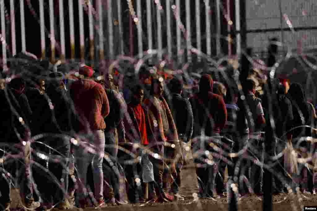 Migrantes son vistos cerca del muro fronterizo después de haber cruzado la frontera para entregarse a los agentes de la Patrulla Fronteriza de EEUU.