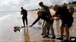 El veterano estadounidense de la Segunda Guerra Mundial Bill Wall arroja rosas al agua durante una ceremonia de colocación de coronas de flores en Playa Utah, el 5 de junio de 2024, en Normandía, Francia.