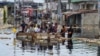Warga menyeberangi banjir di distrik Pompage di Kinshasa, Republik Demokratik Kongo, pada 9 Januari 2024. (Foto: AFP)