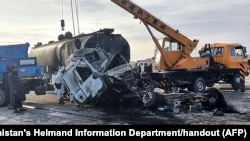 This handout photo released by Afghanistan's Helmand Information Department shows the wreckage of a passenger bus and oil tanker after the bus collided with a motorbike, then crashed into the tanker in Helmand province, killing 21 people, on March 17, 2024.