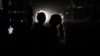 A Palestinian girl holding a child is silhouetted in against the lights of an oncoming car in Rafah, in the southern Gaza Strip, on May 4, 2024.