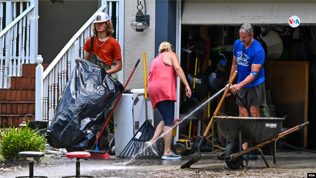 Las personas limpian el barro y los escombros del exterior de una casa en Crystal River, Florida, el 31 de agosto de 2023.