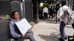 Una manifestante fuera de la escuela pública 172 mientras los estudiantes salen de clases, el martes 16 de mayo de 2023, en Nueva York.
