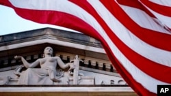 ARCHIVO - Una bandera estadounidense ondea afuera del edificio del Departamento de Justicia en Washington, el 22 de marzo de 2019.