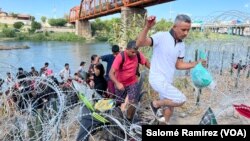 Migrantes cruzan de manera irregular sobre el alambre de púas hacia Eagle Pass, Texas, con la intención de ser procesados por autoridades fronterizas el 25 de septiembre de 2023.