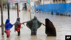 FILE - Women walk through floodwaters after heavy rainfall in Mogadishu, Somalia, Nov. 20, 2023. 