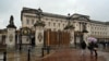 People walk past the a set of boarded up gates to Buckingham Palace in London, March 10, 2024, after a car crashed into them. 