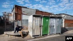 ARCHIVO - Un hombre es visto sentado en una acera en Khayelitsha, cerca de Ciudad del Cabo, Sudáfrica, el 21 de abril de 2022.
