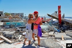 La muralista local Candy Miller, a la izquierda, abraza a Ana Kapel, la gerente de Pier Peddler, una tienda de regalos que vendía moda femenina, en el sitio de lo que solía ser la tienda en Fort Myers Beach, Florida. , 30 de septiembre de 2022.