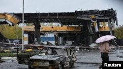Una mujer pasa frente a una gasolinera destruida por el ataque militar ruso de ayer, en Dnipro, Ucrania, el 26 de octubre de 2022.
