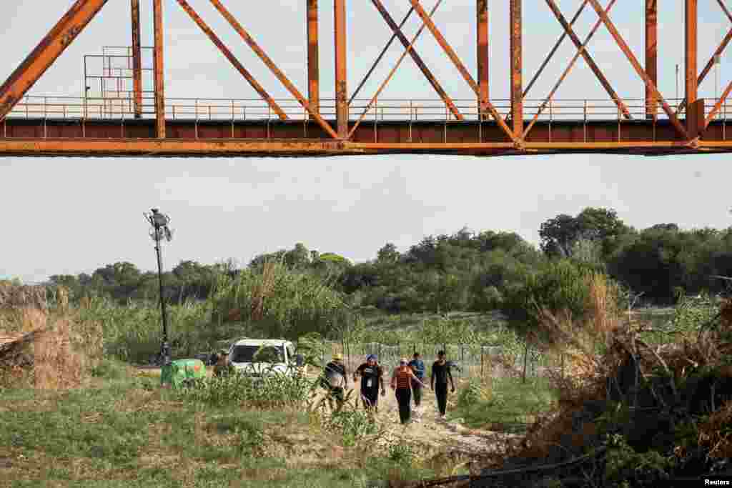 Migrantes que buscan asilo son escoltados, en Eagle Pass, Texas, por un agente de la Guardia Nacional de Estados Unidos.