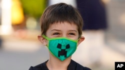 El estudiante de jardín de infantes Adam Shallbetter posa mientras su madre toma una foto después de llegar a la Escuela Primaria Whittier, el 24 de agosto de 2021, en Salt Lake City, Utah.