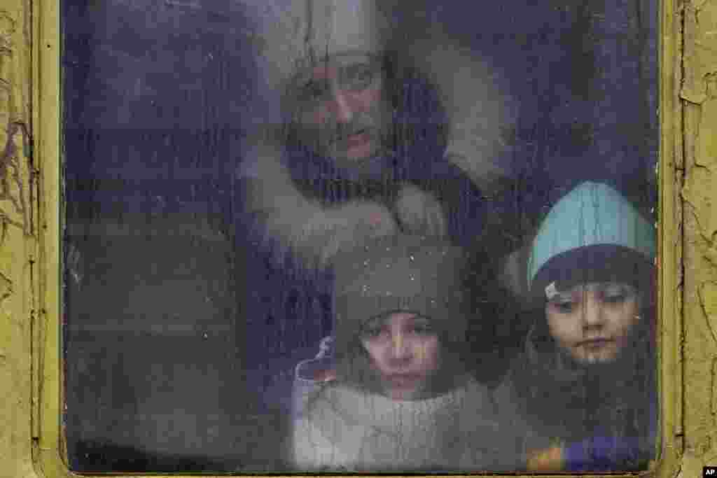 Los niños miran por la ventana de un tren sin calefacción con destino a Lviv, en Kiev, Ucrania, el jueves 3 de marzo de 2022.