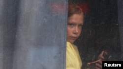 Una niña mira por la ventana de un autobús mientras los civiles evacuados de la región ucraniana de Jesón, controlada por Rusia, llegan a una estación ferroviaria local, en la ciudad de Dzhankoi, Crimea, 2 de noviembre de 2022. REUTERS/Alexey Pavlishak