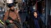 Un combatiente talibán hace guardia mientras una mujer pasa caminando en Kabul, Afganistán, el 26 de diciembre de 2022. Los talibanes rechazaron una resolución del Consejo de Seguridad de la ONU que condena la prohibición contra el derecho laboral de las mujeres locales.