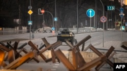 Un vehículo blindado de las Fuerzas Armadas de Ucrania conduce detrás de las barricadas a lo largo de una calle en la capital de Ucrania, Kiev, el 19 de marzo de 2022.
