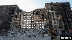 Un miembro del servicio de las tropas prorrusas camina cerca de un edificio de apartamentos destruido en el transcurso del conflicto entre Ucrania y Rusia en la ciudad portuaria sitiada del sur de Mariupol, Ucrania, el 28 de marzo de 2022.
