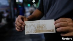 Un hombre muestra un nuevo billete de 5 bolívares el día que el gobierno lanzó la segunda reforma monetaria en tres años al eliminar seis ceros de la moneda bolívar en respuesta a la hiperinflación, en Caracas, el 1 de octubre de 2021. 