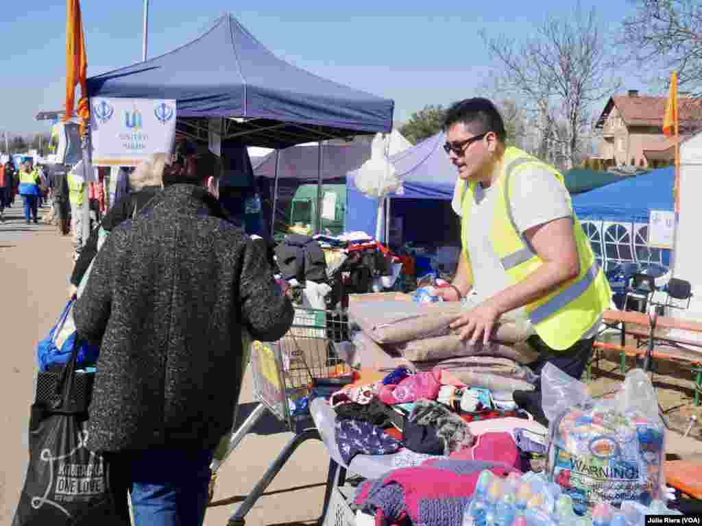 Voluntario ofrece mantas a una refugiada recién llegada a Polonia.