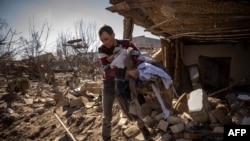 Un hombre recoge ropa de una casa dañada en la ciudad de Zhytomyr, en el norte de Ucrania, el 23 de marzo de 2022. (Foto de FADEL SENNA / AFP)