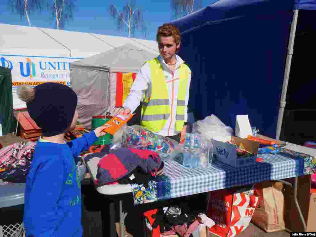Voluntario ofrece chocolate a un refugiado. Debido a la gran cantidad de niños que llegan a Polonia, muchos puestos regalan golosinas para sacar una sonrisa a los más pequeños.